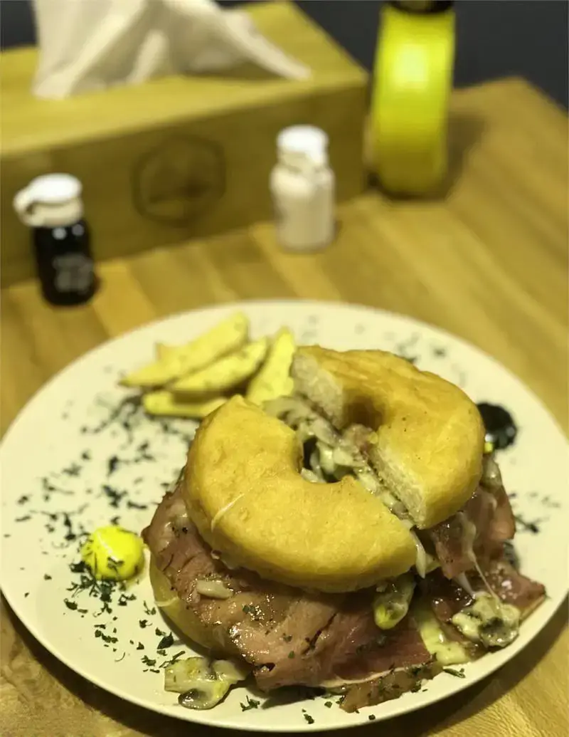 ساندویچ دونات برگر ویژه اریک برگر با ژامبون گوشت، پنیر آب شده و قارچ، همراه سیب زمینی سرخ کرده روی میز چوبی رستوران