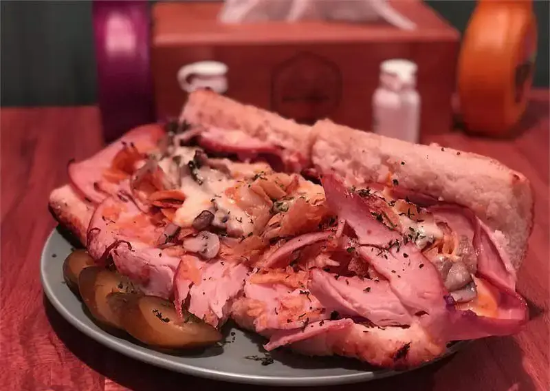 ساندویچ عظیم و وسوسه‌انگیز برگر اریک برگر، پر از ورقه‌های گوشت تازه، پنیر ذوب شده، قارچ و چاشنی‌های معطر، آماده سرو در محیط فست فود.