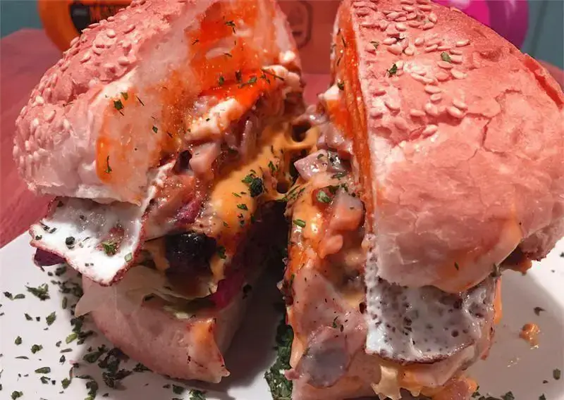 تصویری از یک همبرگر لذیذ و پرملات اریک برگر با نان صورتی کنجدی، پنیر ذوب شده و تخم مرغ نیمرو. یک برگر خاص و اشتهاآور.