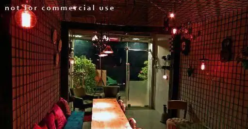 تصویری از محیط داخلی کافه رستوران توپیچ: دکوراسیون خاص با نورپردازی گرم و لامپ‌های ادیسونی، میز چوبی و کاناپه‌های قرمز رنگ، فضایی دنج و دلنشین.