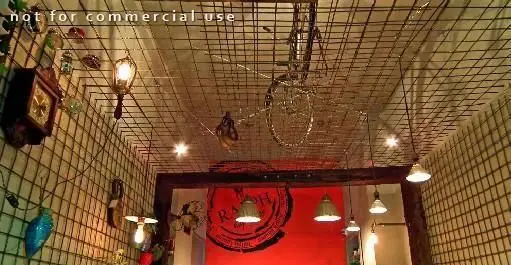 دکوراسیون داخلی کافه رستوران توپیچ با سقف و دیوارهای مشبک، نورپردازی گرم، اجسام دکوری خاص و دوچرخه آویزان، محیطی دنج و جذاب را ارائه می‌دهد.