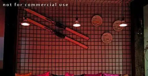 فضای داخلی مدرن کافه رستوران توپیچ: دیوار مشبک با نورپردازی گرم، میله‌های دکوراتیو و بشقاب‌های تزئینی. محیطی دلپذیر برای مشتریان.