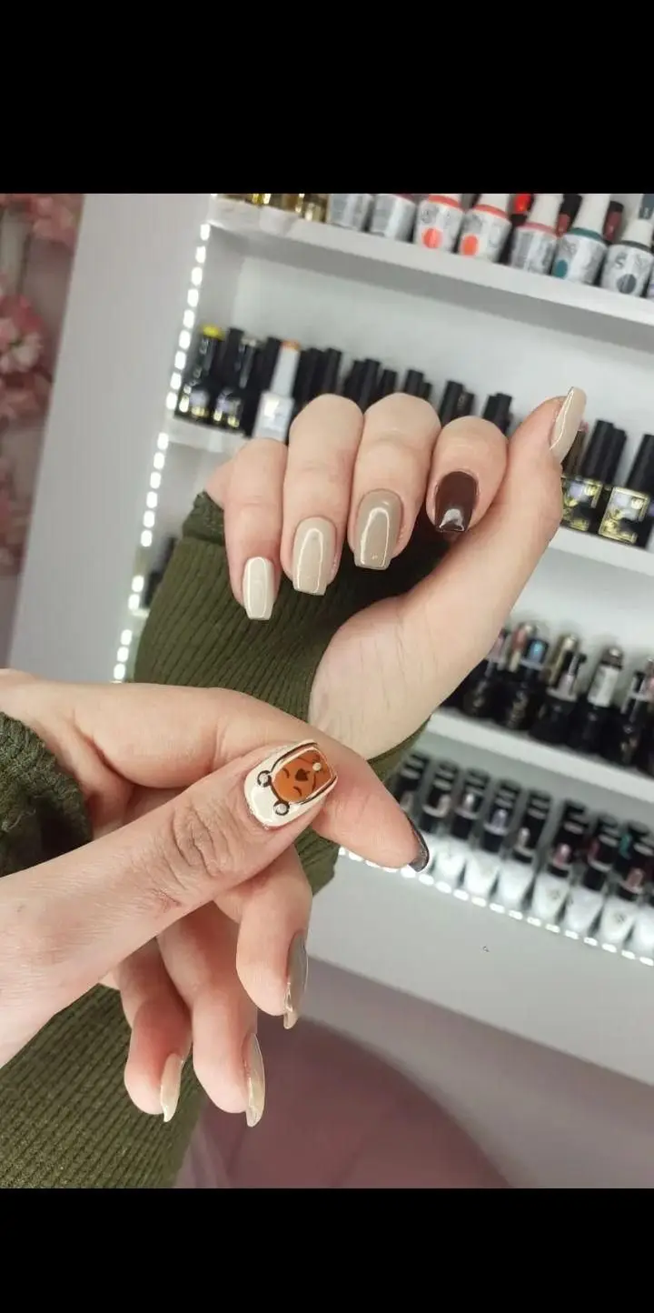 طراحی ناخن فانتزی با لاک ژل قهوهای و کرم به همراه طرح خرس مینیاتوری بامزه روی ناخن شست مناسب برای ایده کاشت ناخن دخترانه