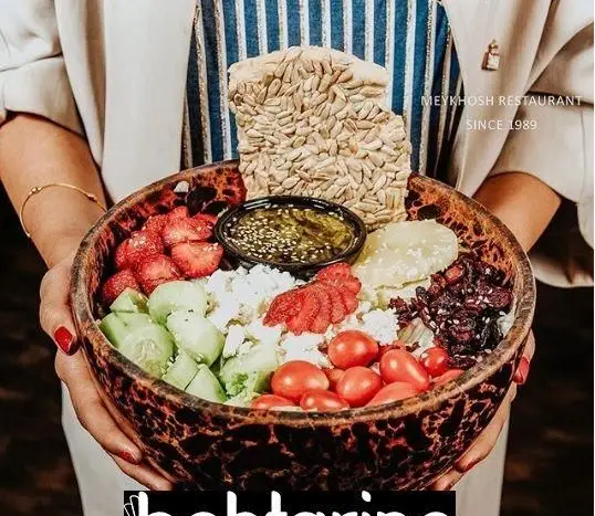 تصویری جذاب از سالاد ویژه و سالم رستوران میخوش، شامل توت فرنگی، خیار، گوجه، پنیر و نان تخمه آفتابگردان در کاسه‌ای زیبا.