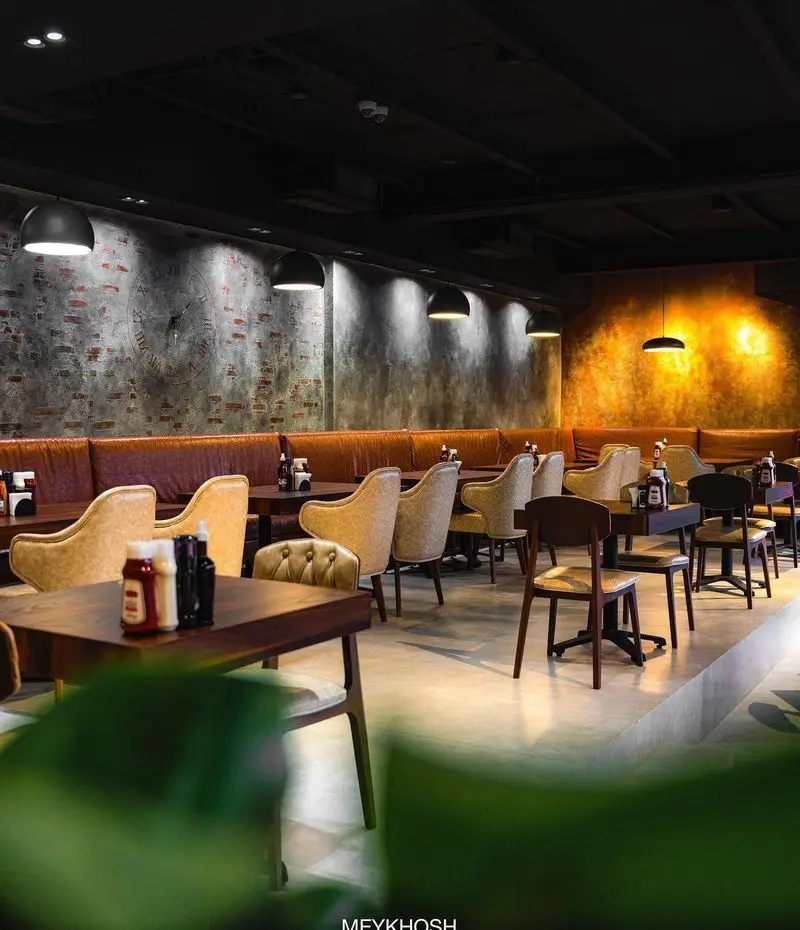 دکوراسیون داخلی چشم‌نواز رستوران میخوش: دیوارهای آجری، نورپردازی گرم، مبلمان راحتی و فضایی دلنشین مناسب پاتوق و صرف غذا.