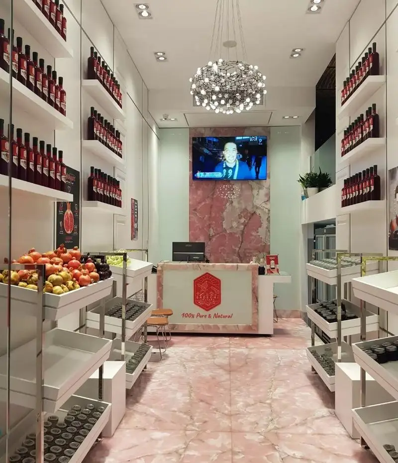 فروشگاه مدرن آب انار و محصولات انار طبیعی صادقی مقدم با نمایش بطری‌های آب انار خالص و انارهای تازه ارگانیک.