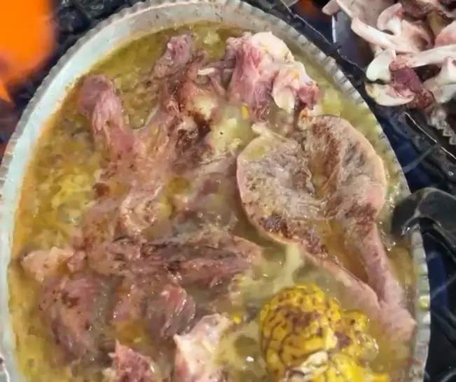 نمایی نزدیک از پخت کله پاچه اصیل در طباخی توکلی. گوشت تازه گوسفندی، مغز و آبگوشت غلیظ در حال جوشیدن روی شعله.