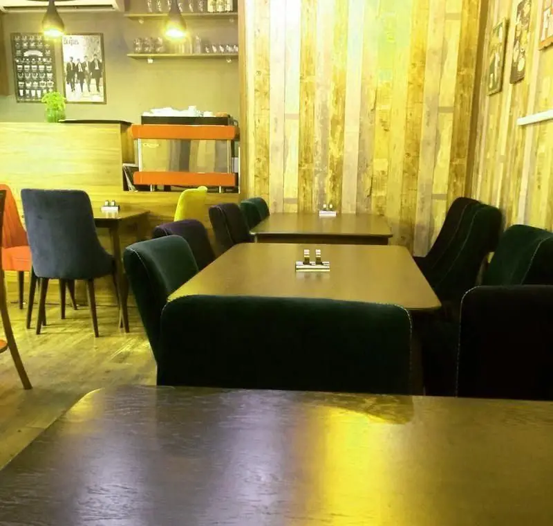 فضای داخلی کافه رستوران ملورین با میز و صندلی‌های متنوع و راحت، دیوار چوبی مدرن و محیطی دنج و گرم برای لحظاتی آرامش‌بخش.