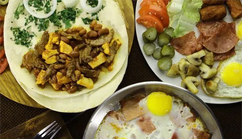 میز صبحانه مفصل کافه رستوران ملورین شامل تخم‌مرغ، ژامبون، قارچ، لوبیا و نان. تجربه‌ای خوشمزه و کامل برای شروع روز.