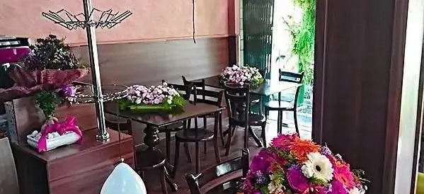 فضای دلنشین و دکوراسیون جذاب کافه رستوران ملورین با میز و صندلی‌های چوبی و گل‌آرایی چشم‌نواز برای رویدادها و پذیرایی.