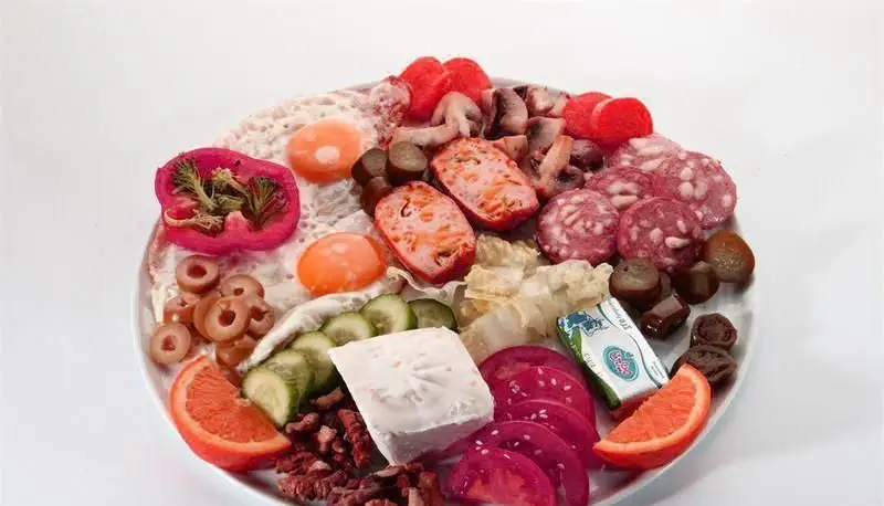 یک سینی صبحانه کامل و رنگارنگ از کافه رستوران ملورین شامل تخم مرغ، سوسیس، پنیر، سبزیجات تازه، زیتون و میوه. لذت یک وعده صبحانه خاص.