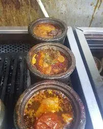 طبخ دیزی سنگی‌های سنتی و گرم در دیزی سرای رضا، آماده سرو. غذای اصیل و لذیذ ایرانی برای تجربه طعمی به‌یادماندنی.