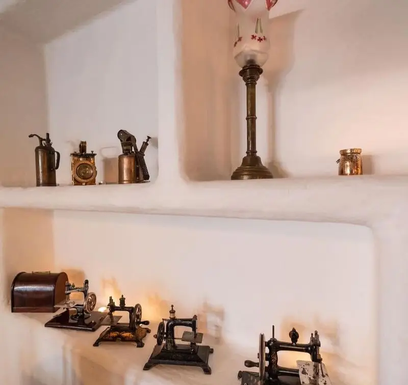 دکوراسیون داخلی رستوران مس توران با اشیاء عتیقه: چرخ خیاطی مینیاتوری، چراغ و ابزار قدیمی برنجی روی طاقچه‌های سنتی.