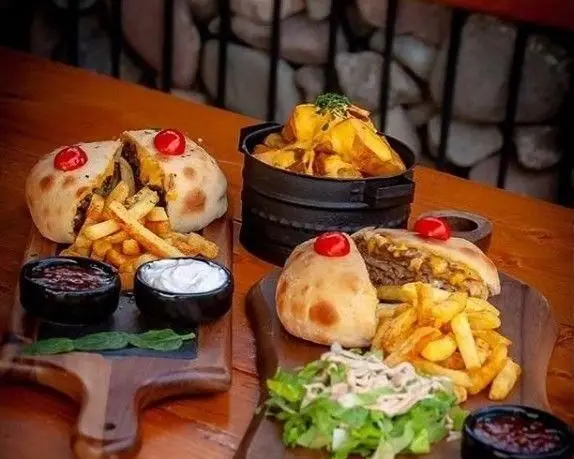 میز غذای خوشمزه رستوران ایتالیایی شله شامل دو پیتزای گرد، سیب زمینی سرخ کرده، سس و سالاد، و سیب زمینی تنوری.