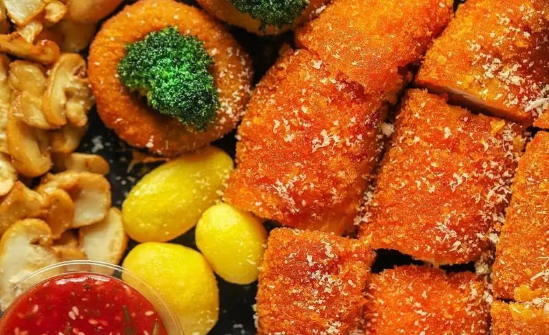 بشقاب رنگارنگ فست فود میخوش شامل مرغ سوخاری ترد، کلم بروکلی، سیب زمینی سرخ شده و سس قرمز. یک وعده غذایی لذیذ و پرطرفدار.