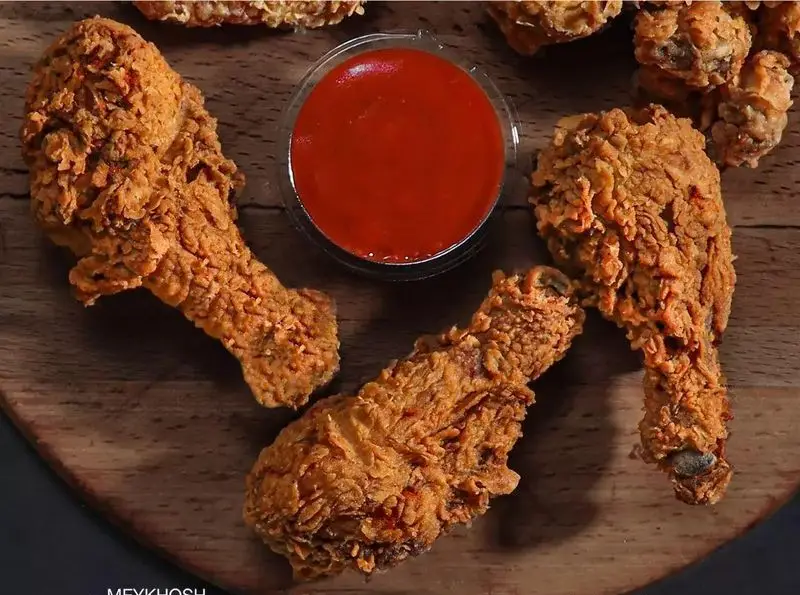 بهترین مرغ سوخاری فست فود میخوش: قطعات طلایی و خوش طعم جوجه با سس قرمز مخصوص، آماده برای سفارش آنلاین غذای خانوادگی.