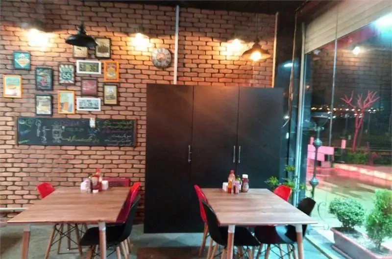 فضای داخلی مدرن و شیک فست فود پرگوک، شامل دیوارهای آجری، میزهای چوبی، صندلی‌های راحت و دکوراسیون هنری برای تجربه‌ای لذت‌بخش.