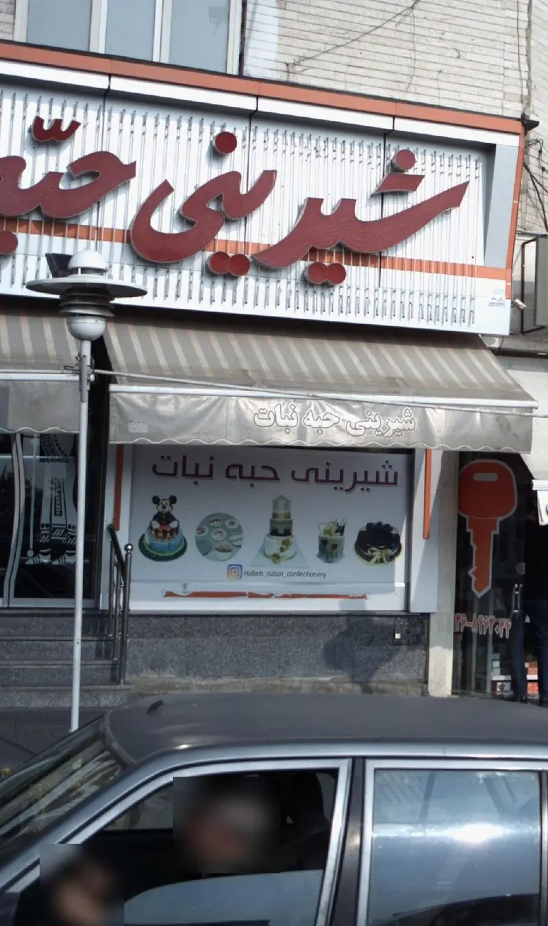 نمای بیرونی شیرینی فروشی حبه نبات با تابلوی بزرگ و ویترین جذاب محصولات شامل انواع کیک، شیرینی و دسر تازه و خوشمزه.