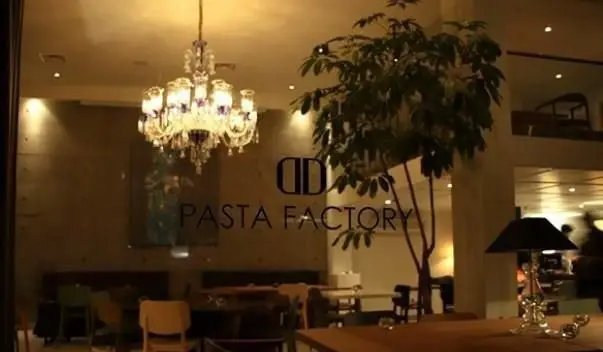 نمای داخلی رستوران ایتالیایی پاستا فکتوری با لوستر درخشان، دکوراسیون مدرن و فضای سبز، محیطی دلپذیر برای تجربه طعم ایتالیایی