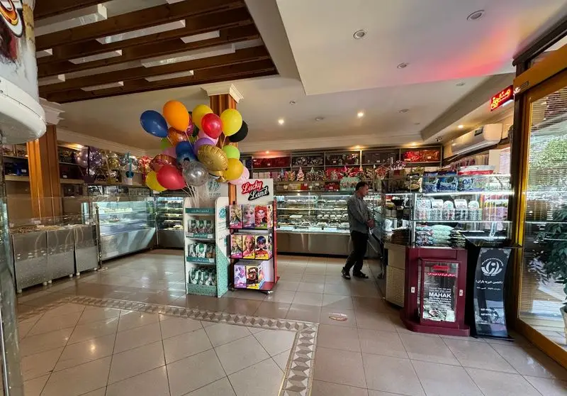 نمای داخلی شیرینی سالوت تهرانپارس، قنادی بزرگ با انواع کیک، شیرینی تازه، دسر و بادکنک‌های رنگی برای مراسم و جشن.