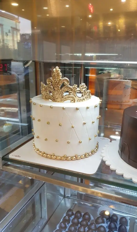 کیک سفید بسیار شیک و مجلل با تاج طلایی سلطنتی و تزیینات مروارید طلایی، موجود در شیرینی سالوت تهرانپارس.