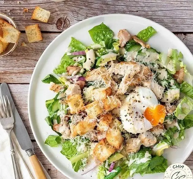 سالاد سزار مرغ با تخم مرغ عسلی، کروتون و پنیر پارمزان، آماده شده در سالادبار چیا. یک غذای سالم و خوشمزه.