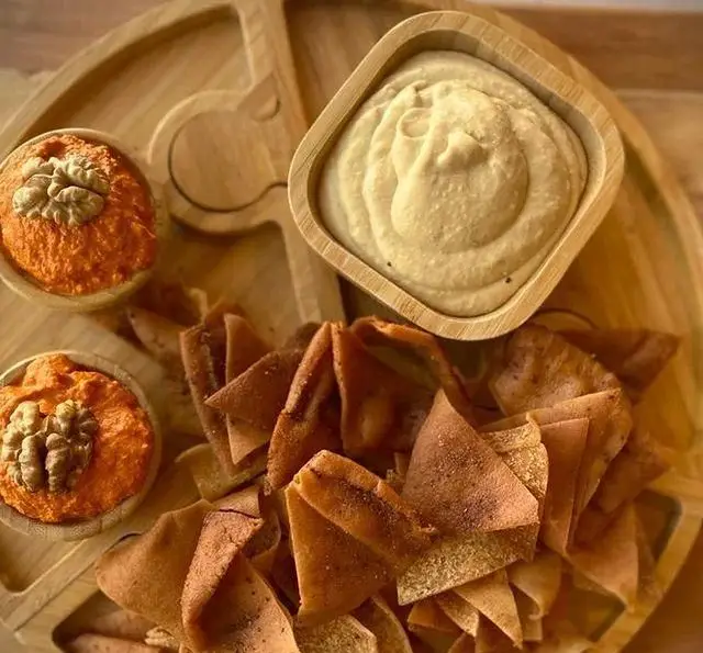 سینی مزه سالادبار چیا شامل حمص، محمره با گردو و نان پیتا برای یک تجربه غذایی سالم و خوشمزه. ایده آل برای پیش غذا.