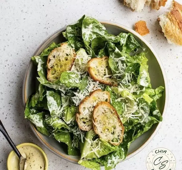 تصویری از سالاد سزار لذیذ سالادبار چیا با کاهو تازه، نان کروتون برشته، پنیر پارمزان رنده شده و سس خامه‌ای سزار.