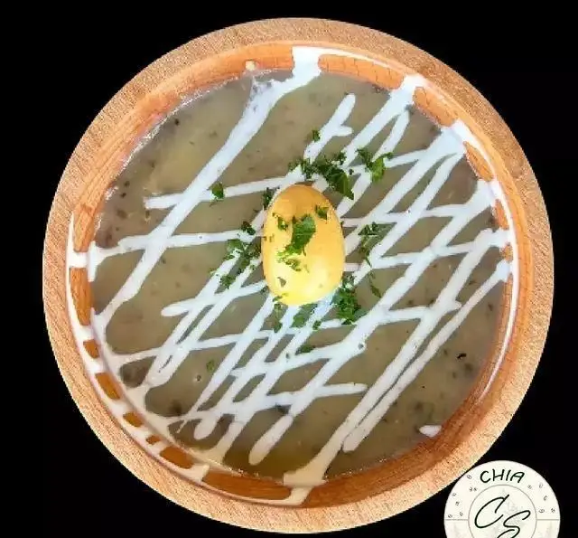 سوپ سبزرنگ سالادبار چیا در کاسه چوبی، با تزئین سس سفید، تخم بلدرچین و سبزیجات تازه. غذایی سالم و خوشمزه.