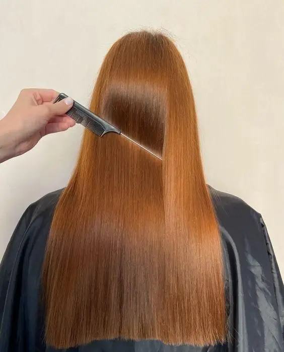 شانه کردن موهای صاف و ابریشمی با رنگ موی مسی جذاب بعد از انجام خدمات تخصصی کراتینه و احیای مو در سالن زیبایی تهران