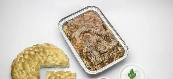 غذای لذیذ رستوران آناتولی: خوراک گوشت گرم در ظرف آلومینیومی، با نان تازه سنتی و ماست با جعفری، آماده دلیوری و سفارش آنلاین.