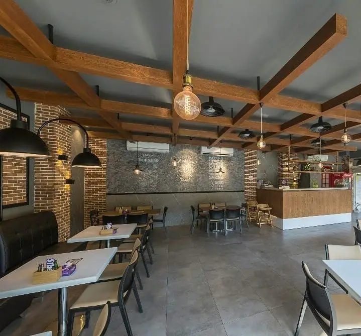 فضای داخلی دنج و مدرن پیتزا سیب ۳۶۰ با دکوراسیون چوبی، میز و صندلی راحت و نورپردازی زیبا. مناسب برای فست فود و رستوران.