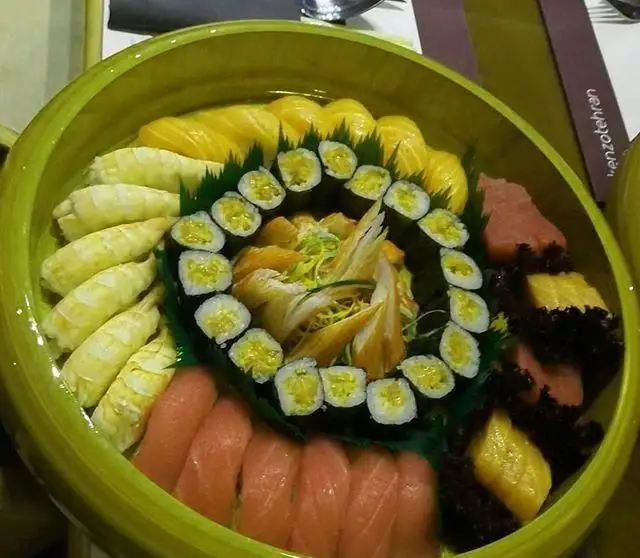 سینی بزرگ و زیبای سوشی و ساشیمی تازه، شامل سالمون، تن، ماکی و رول‌های خاص در رستوران ژاپنی کنزو اکسپرس.