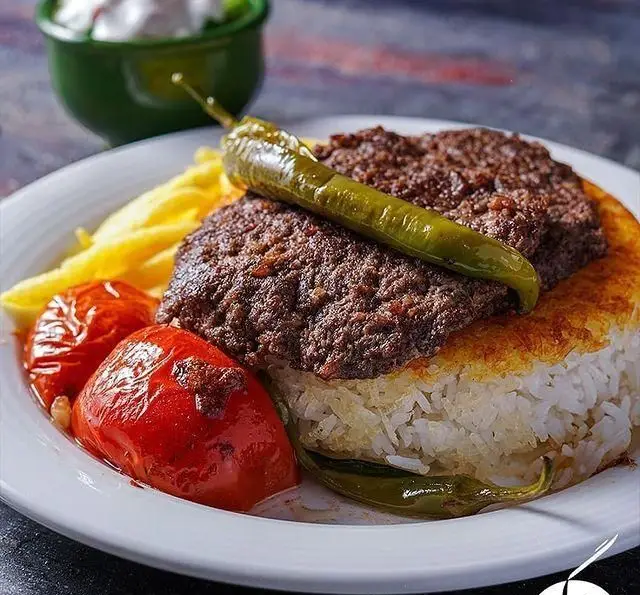 کباب کوبیده آبدار به همراه ته دیگ برشته و طلایی، گوجه کبابی و سیب زمینی سرخ شده در رستوران ته دیگ بام لند.