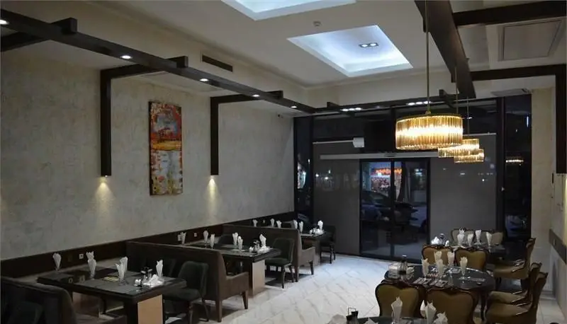 نمای داخلی شیک و مدرن رستوران ایرانی سانلی با دکوراسیون چوبی، نورپردازی زیبا و میز و صندلی‌های چیده شده برای مشتریان در فضایی دلنشین.