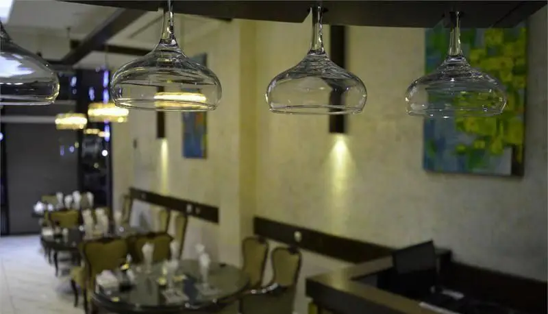 دکوراسیون داخلی رستوران ایرانی سانلی، شامل میز و صندلی‌های شیک، نورپردازی منحصر به فرد با لیوان‌های آویزان، فضایی آرام و دلنشین.