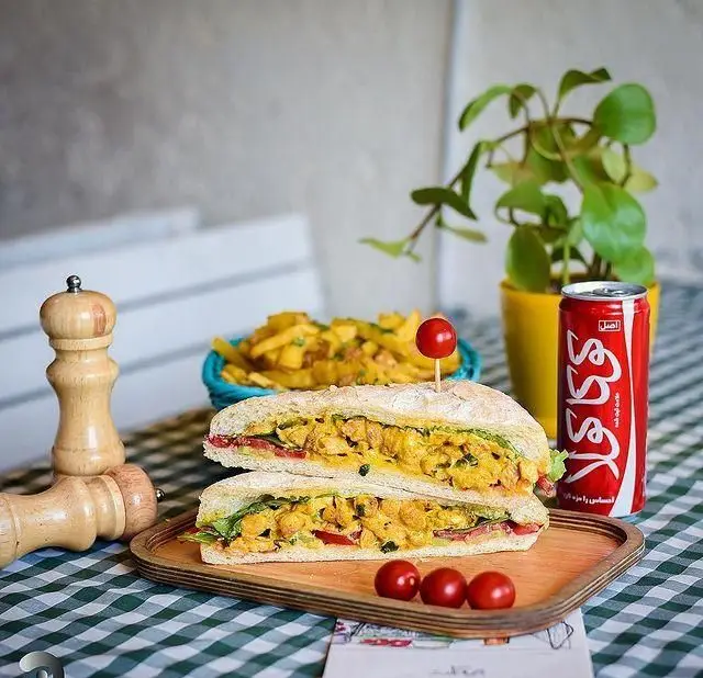 ساندویچ مرغ تازه و سس زرد با گوجه، کاهو، سیب‌زمینی سرخ‌کرده و نوشابه کوکا، غذایی لذیذ از منوی رستوران ایتالیایی نیمکت.