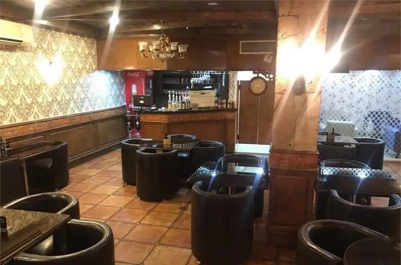 فضای داخلی دنج و شیک کافی شاپ باربتا با دکوراسیون لوکس، میز و صندلی‌های مدرن مشکی، بار کامل و نورپردازی گرم برای مشتریان.