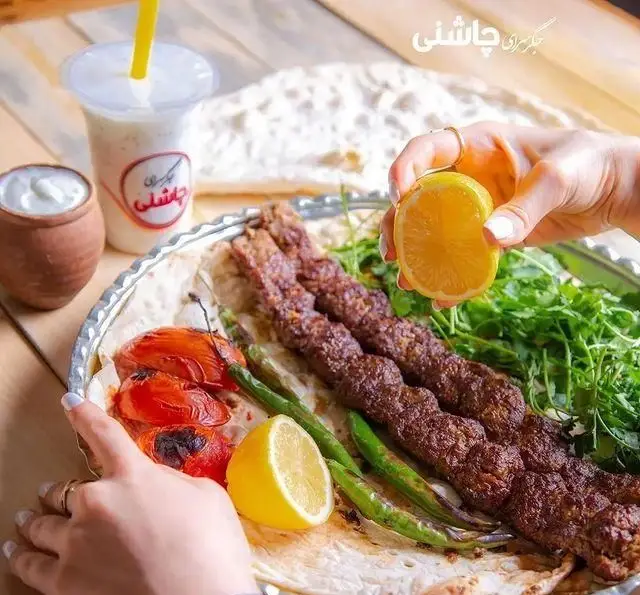 کباب کوبیده لذیذ جگرکی چاشنی تهرانپارس با نان داغ، گوجه و فلفل کبابی، سبزی تازه، لیمو و دوغ. یک غذای اصیل ایرانی.