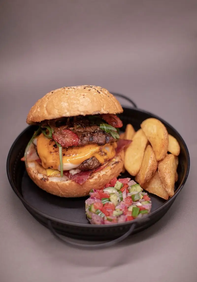 همبرگر دوبل پنیر و بیکن کافه الوا با سیب‌زمینی وجز و سالاد سبزیجات تازه. تجربه‌ای لذیذ از منوی غذایی رستوران الوا.