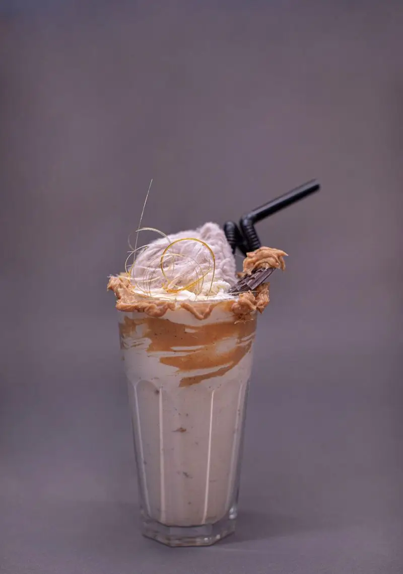 میلکشیک محبوب کافه الوا (Elva Cafe) با تزیینات وسوسه‌انگیز کارامل، شکلات و کره بادام زمینی. نوشیدنی هیجان‌انگیز تابستانی.