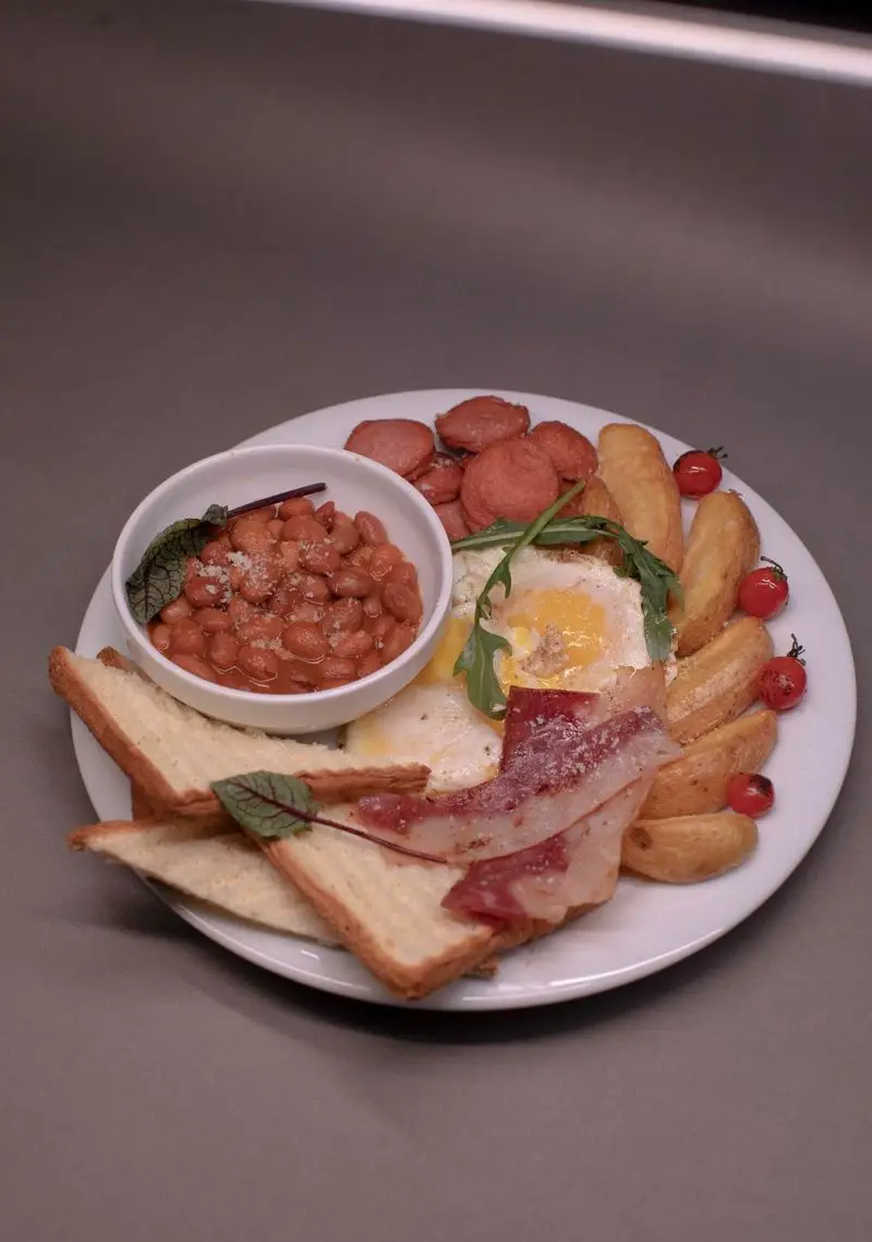 صبحانه مجلل و کامل کافه الوا با تخم مرغ سرخ شده، بیکن ترد، سوسیس، لوبیا، سیب زمینی و نان تست برشته.