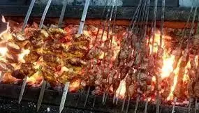 صف طولانی سیخ‌های کباب جگر، بال، جوجه و دل و قلوه در جگرسرای کاج، کباب‌پزی روی آتش ذغال داغ.