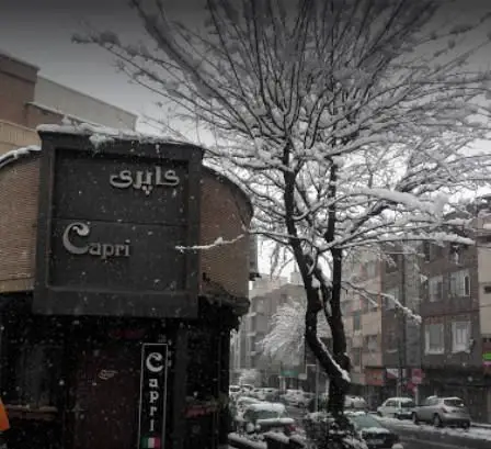 نمای بیرونی رستوران ایتالیایی کاپری در تهران، در روزی زمستانی و برفی، با تابلوی مشخص کاپری و درختان پوشیده از برف در کنار خیابان.