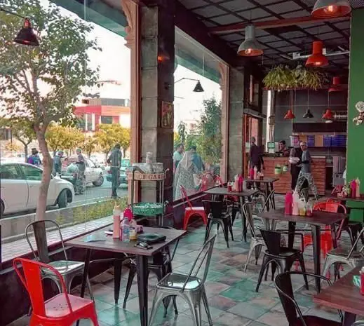 فضای داخلی دنج و مدرن پیتزا سه فر با میز و صندلی‌های شیک، مناسب برای دورهمی‌های خانوادگی و دوستانه در یک عصر دلنشین.