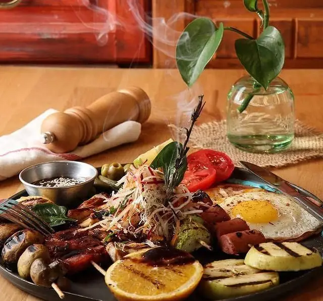 میکس گریل جذاب کافه رستوران رولینجا: شامل انواع کباب گوشت، مرغ، سوسیس، تخم مرغ، سبزیجات و میوه‌های کبابی داغ.