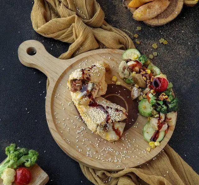 رول‌های غذایی گوشت و پنیر رولینجا با کنجد و سس مخصوص، در کنار سینی سبزیجات تازه و سالم. غذای خاص کافه رستوران رولینجا.