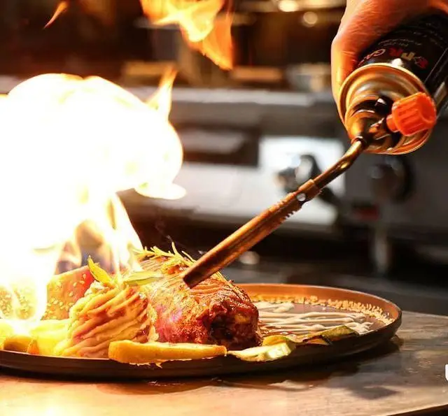 تجربه فلامبه کردن استیک مخصوص با شعله آشپزی توسط سرآشپز در کافه رستوران رولینجا، برای لذت طعمی بی‌نظیر.