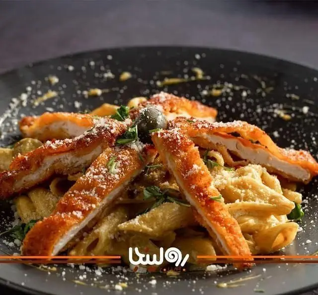 پاستا پنه کرمی با فیله مرغ سوخاری طلایی، تزئین شده با پنیر و زیتون. یک غذای لذیذ در کافه رستوران رولینجا برای تجربه ای خوشمزه.