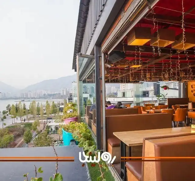 تصویری از کافه رستوران رولینجا با منظره خیره‌کننده دریاچه، شهر و کوهستان. محیطی دلپذیر با دکوراسیون داخلی مدرن و فضای باز شیک.
